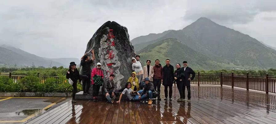 A group of people pose in different poses in front of a mountain landscape in Lijiang on a rainy day.